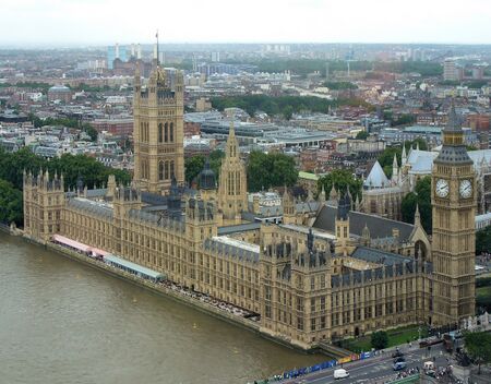 A large clock tower and other buildings line a great river.